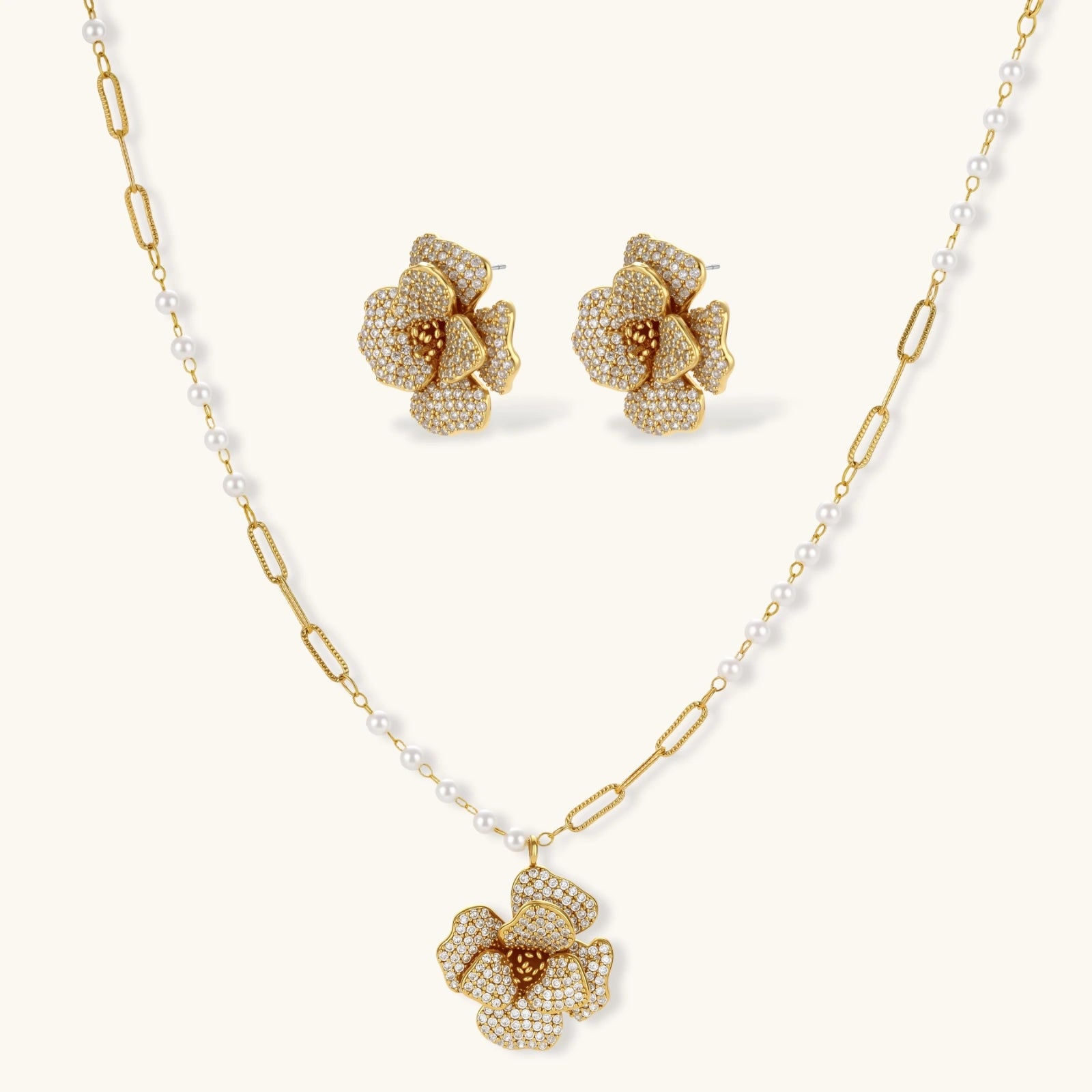Gold floral necklace and earrings with pearl accents on a white background