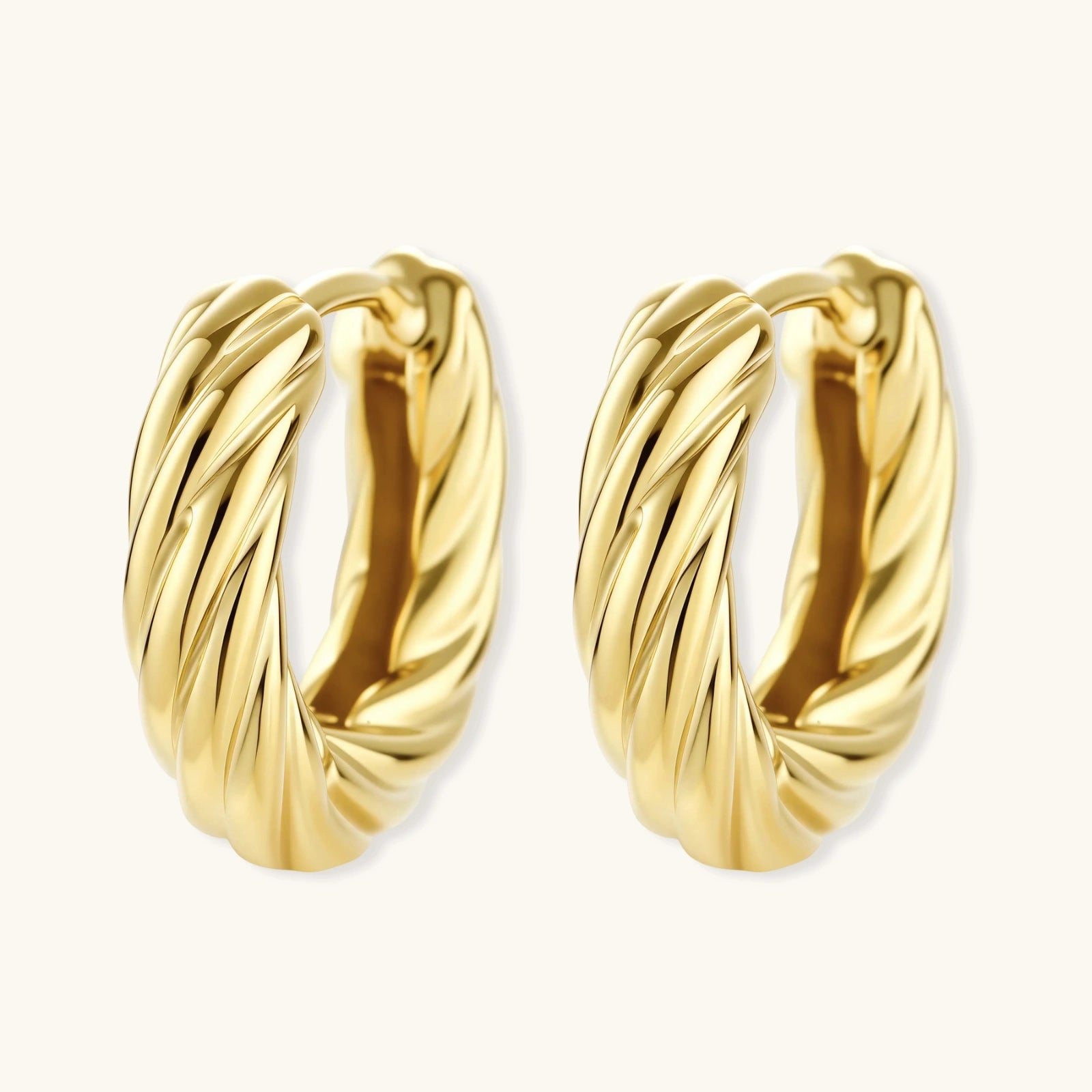 Pair of gold hoop earrings on a beige background