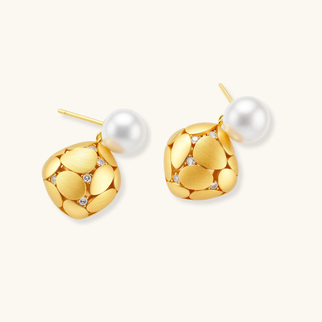 Gold earrings with pearl centers on a white background