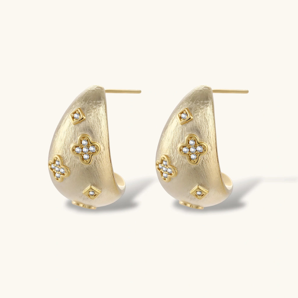 Gold hoop earrings with floral designs on a white background