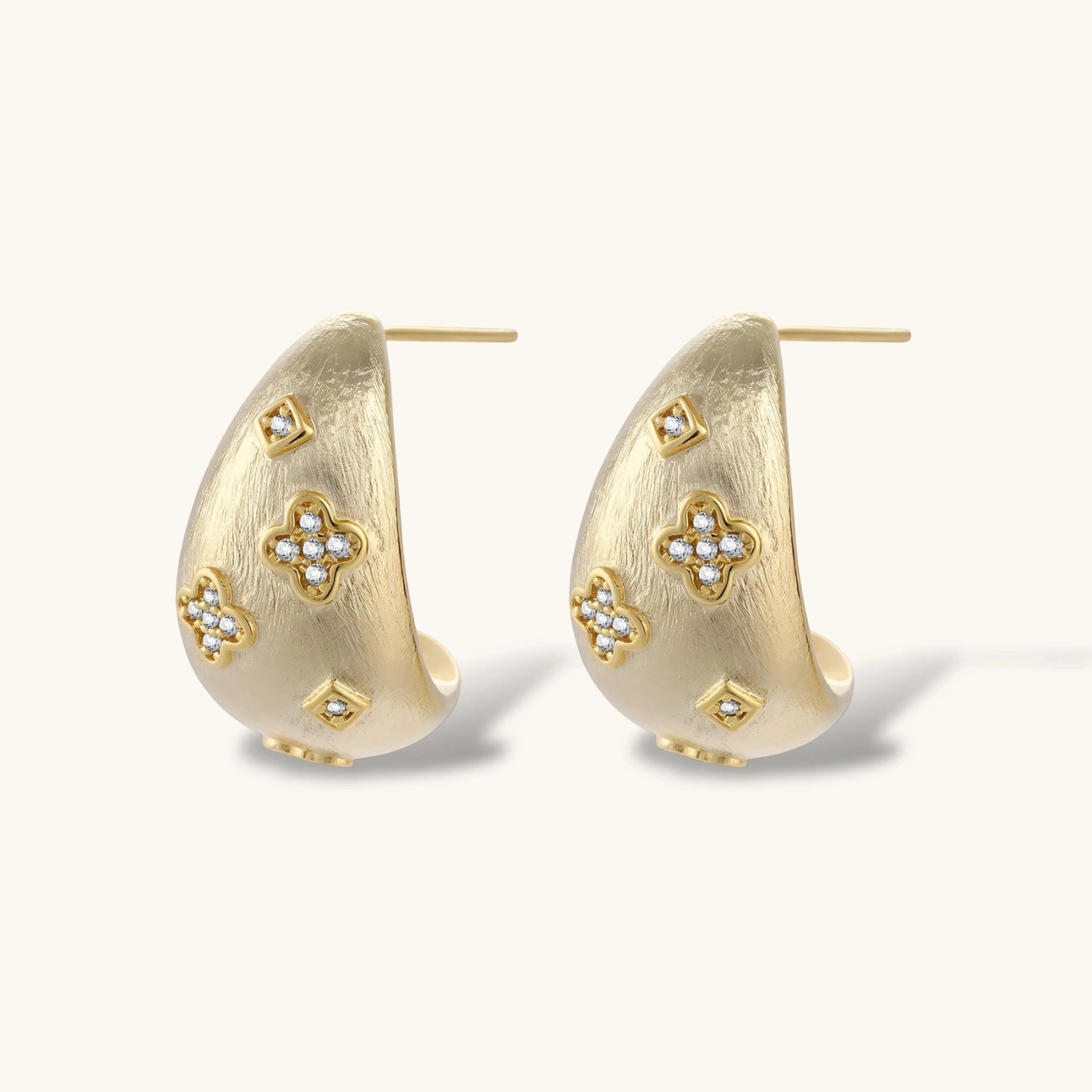 Gold hoop earrings with floral designs on a white background