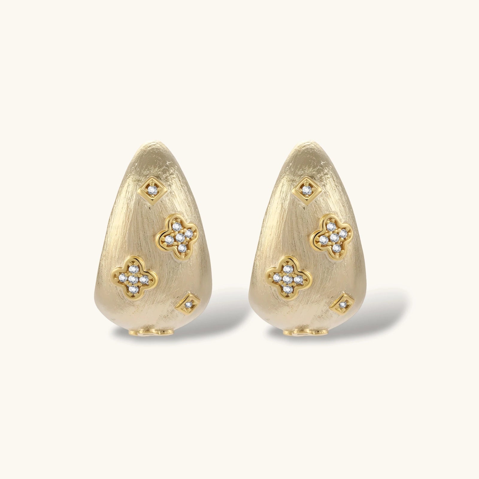 Gold earrings with floral designs on a white background