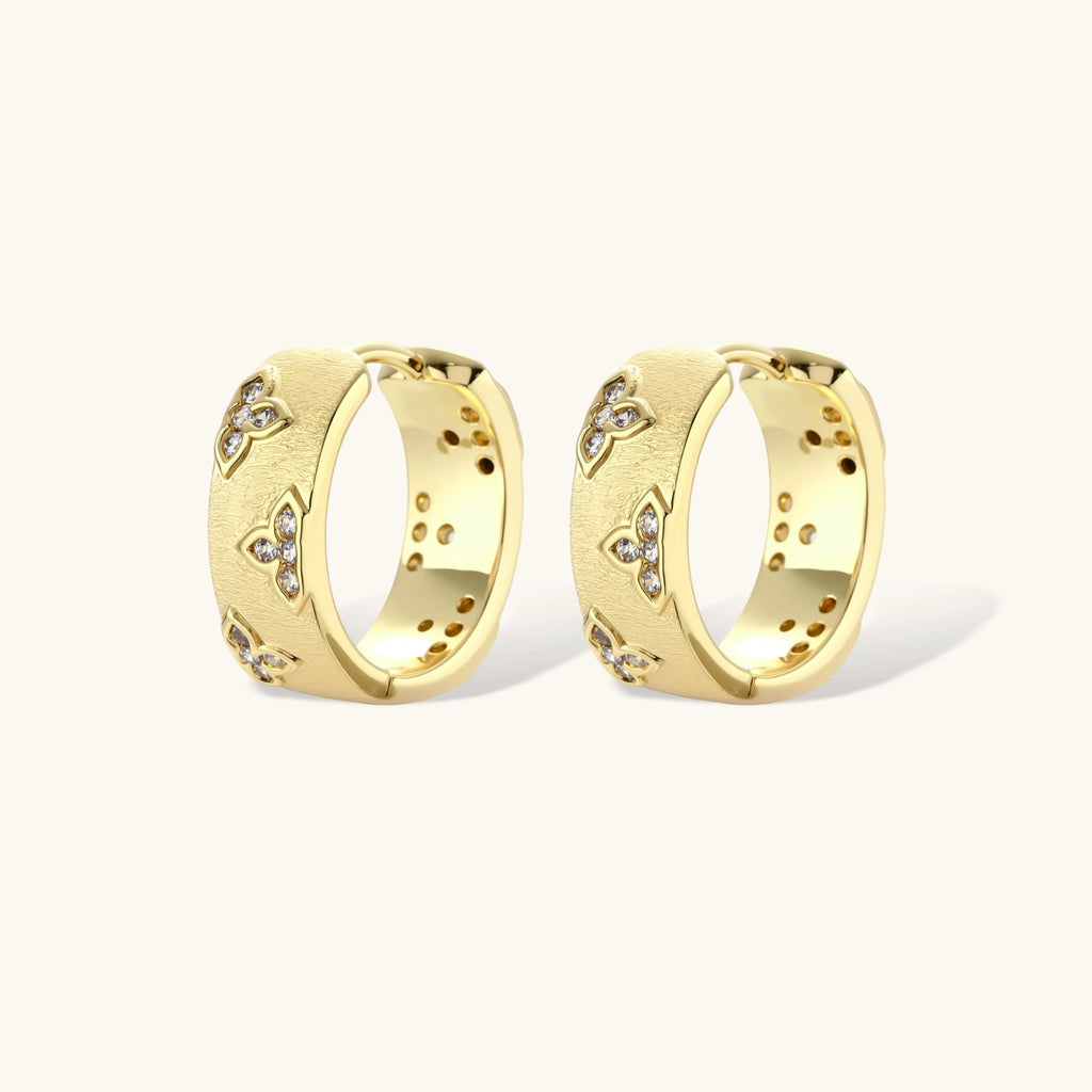 Pair of gold hoop earrings with embedded stones on a white background