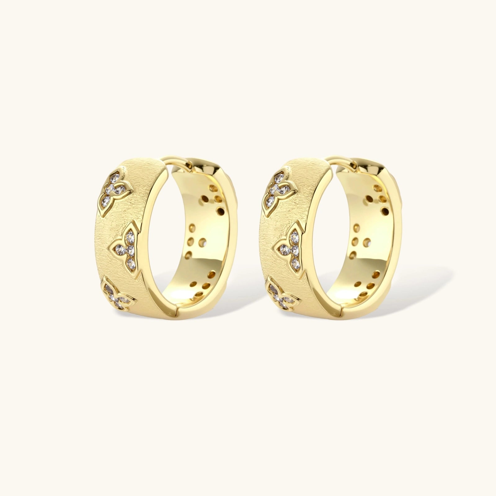 Pair of gold hoop earrings with embedded stones on a white background