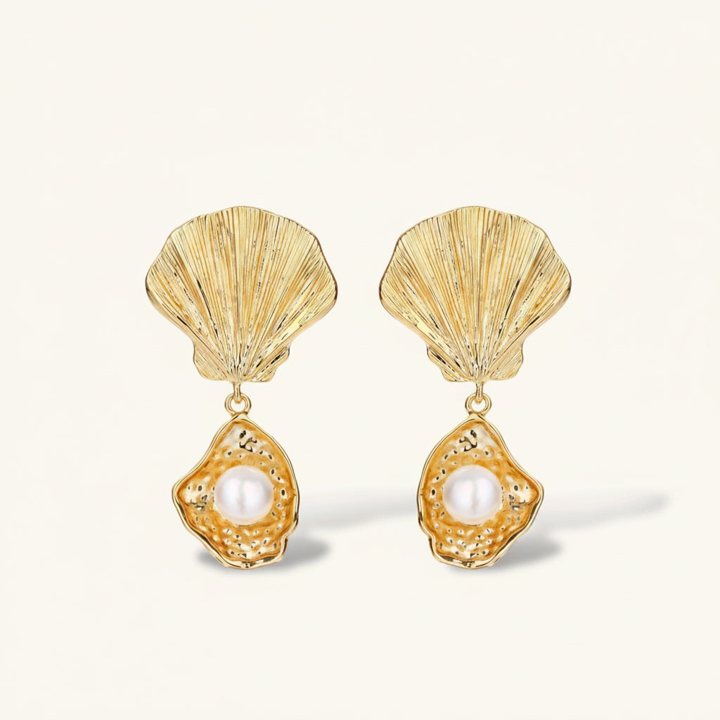 Gold shell earrings with pearl centers on a white background