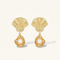 Gold shell earrings with pearl centers on a white background