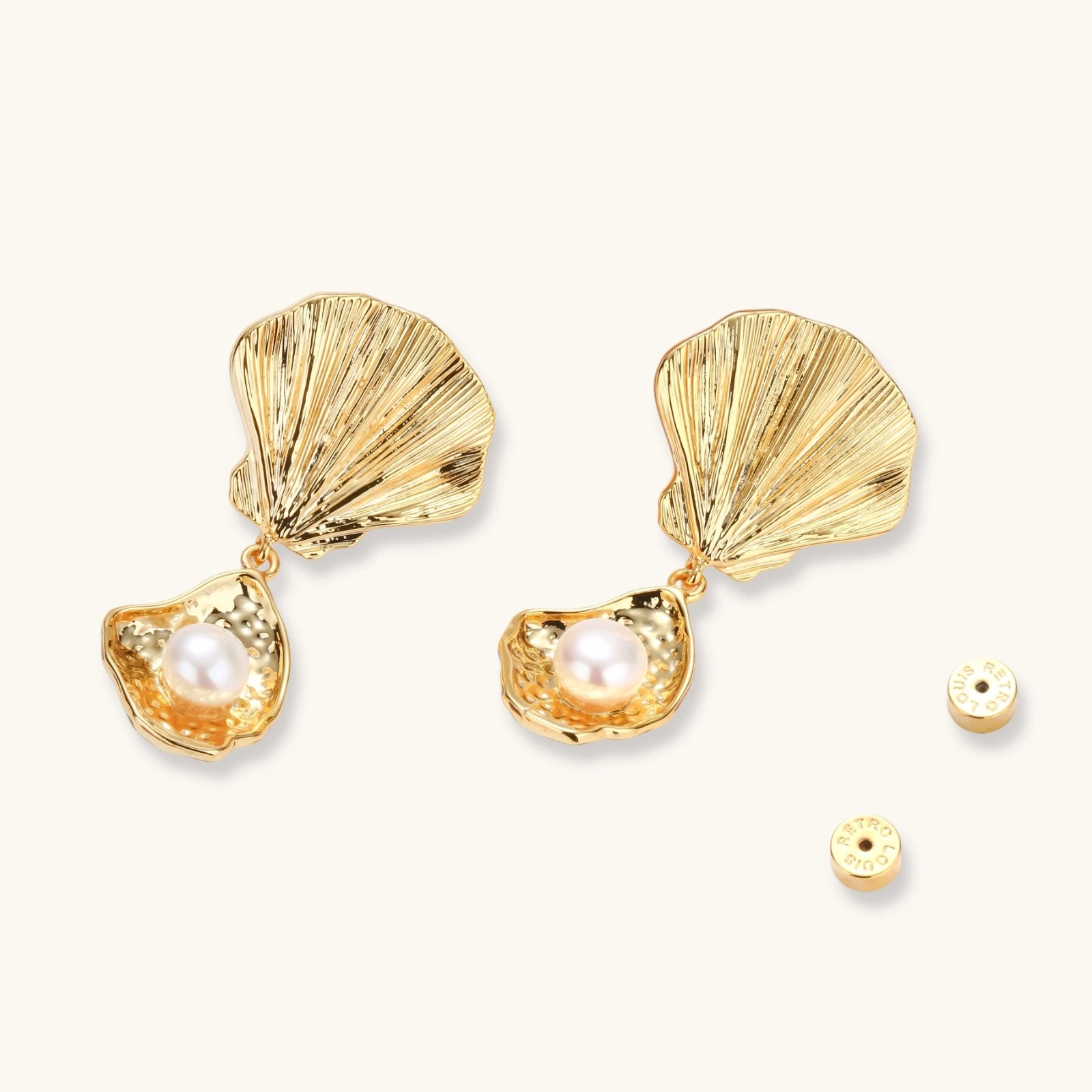 Gold shell-shaped earrings with pearls on a light beige background