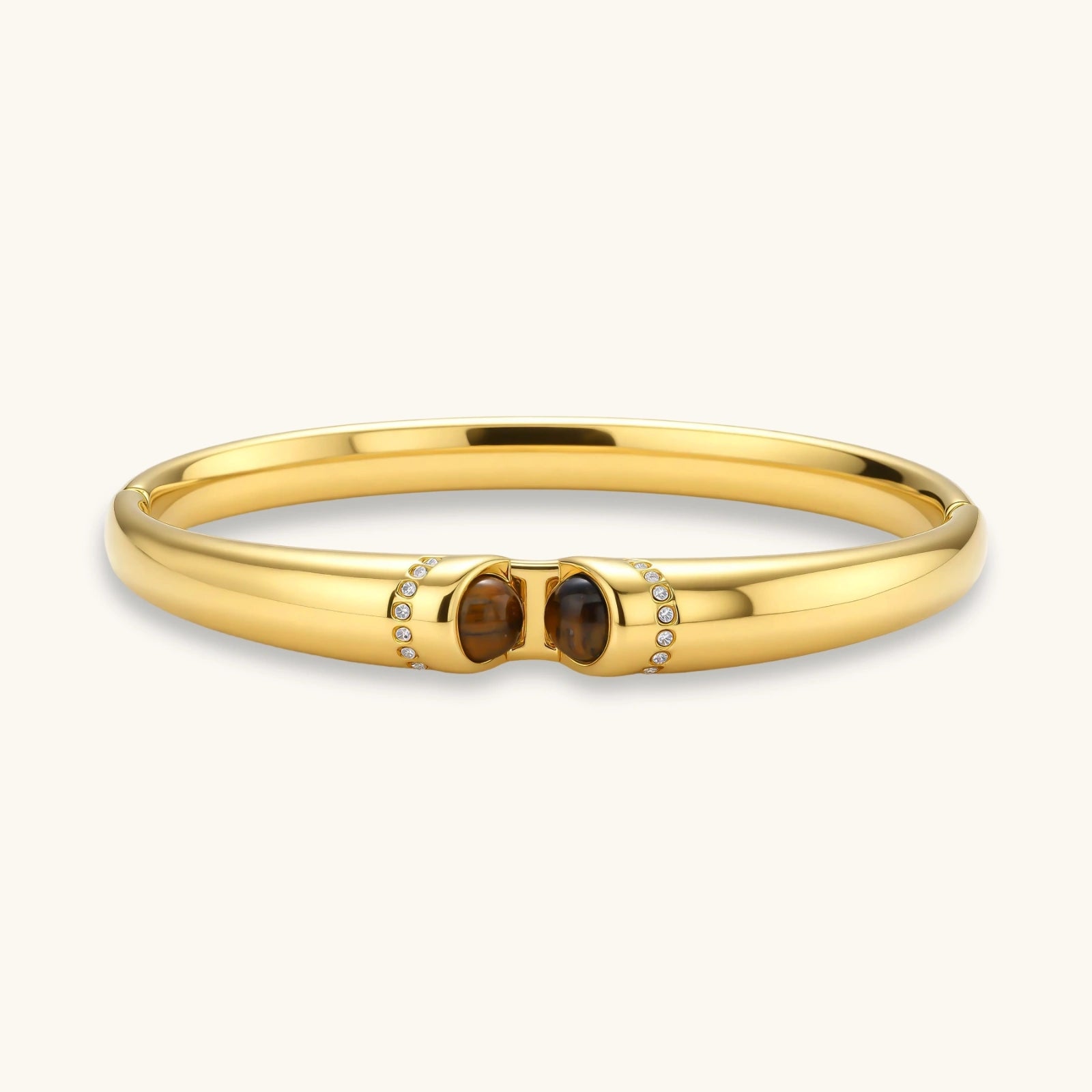Gold bracelet with two brown gemstones on a white background